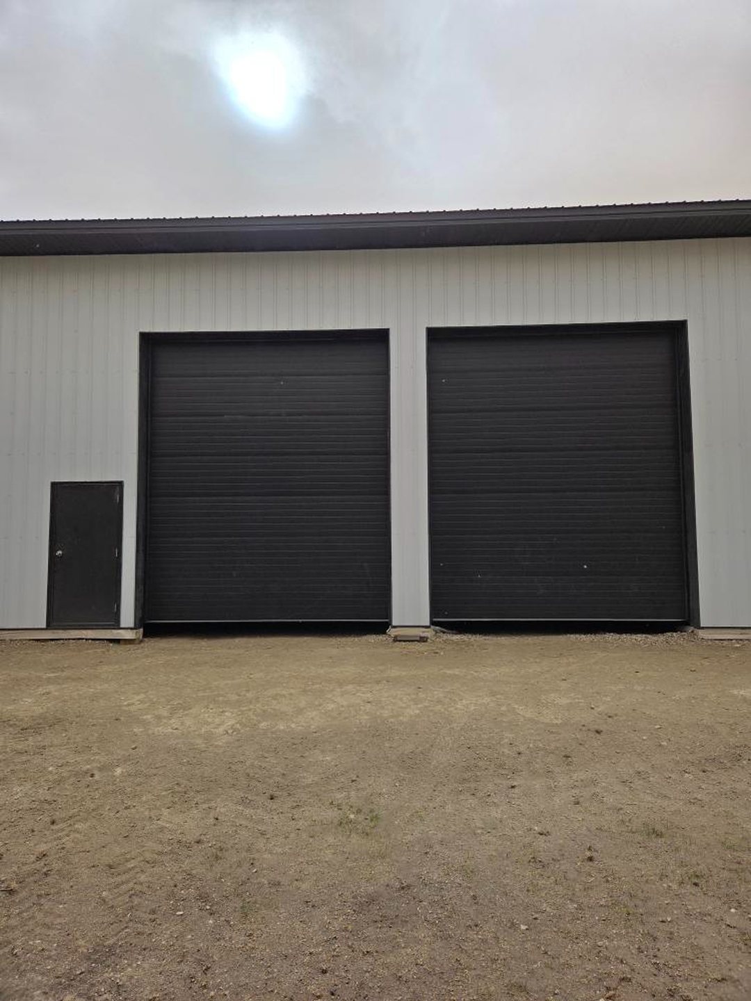 Two black overhead doors on a commercial shop