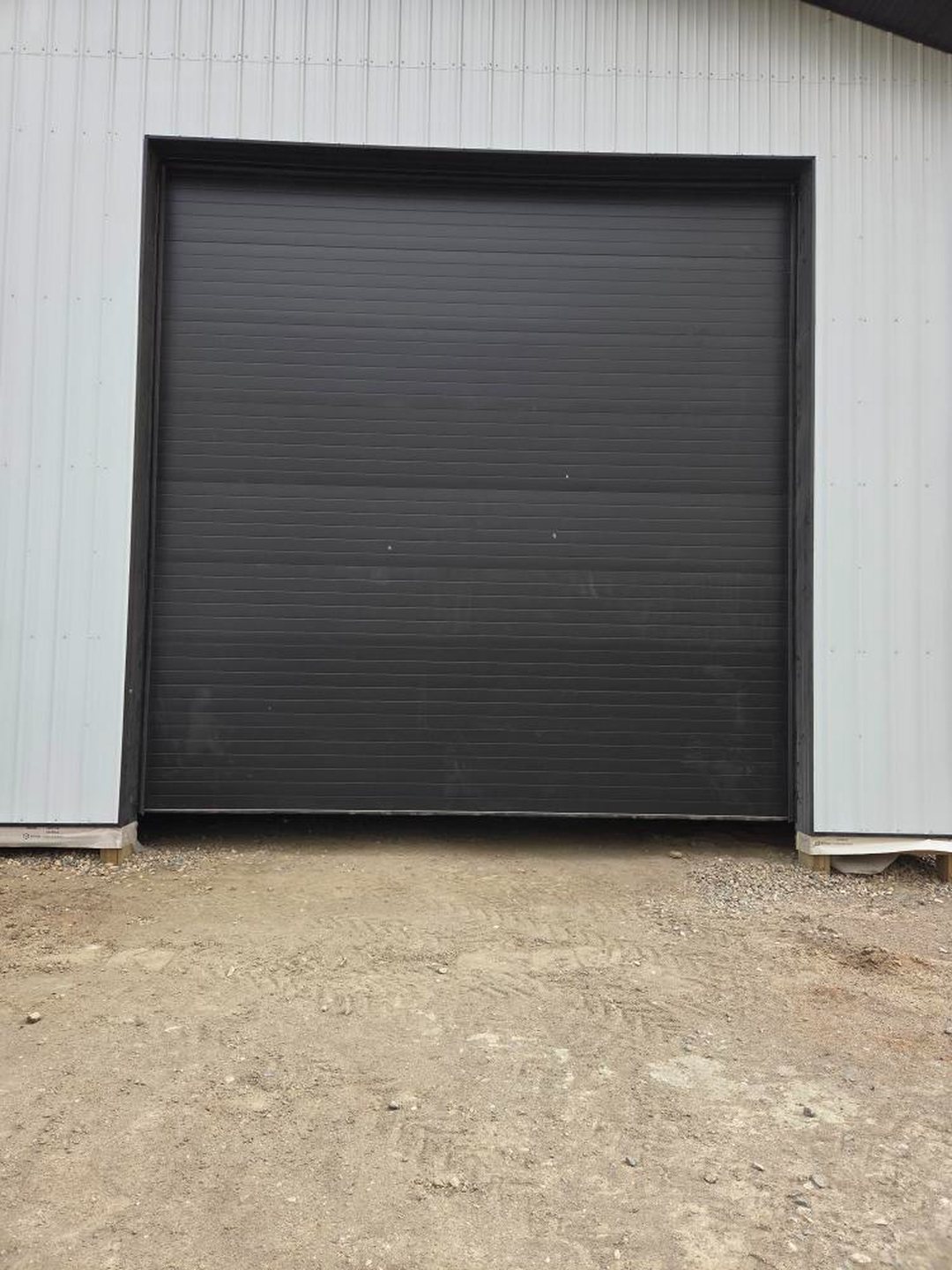 Dark commercial overhead door on a white steel building