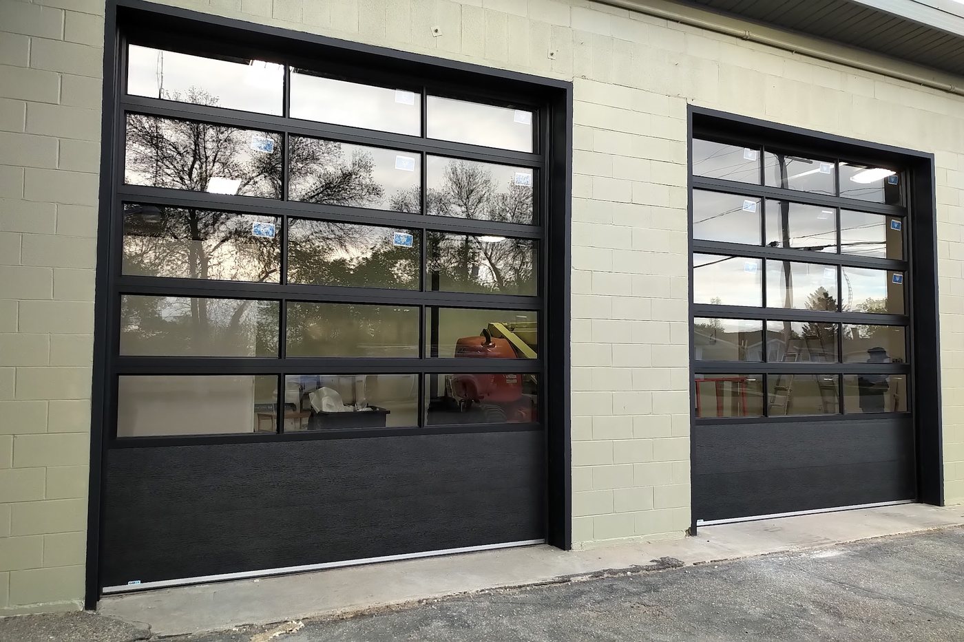 Black full-view aluminium overhead doors on a commercial shop