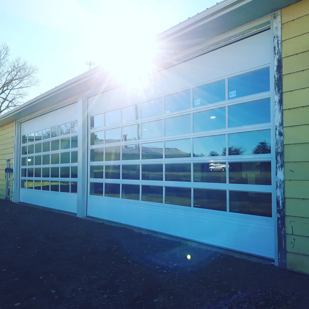 Full-view glass overhead doors on a commercial building in sunlight