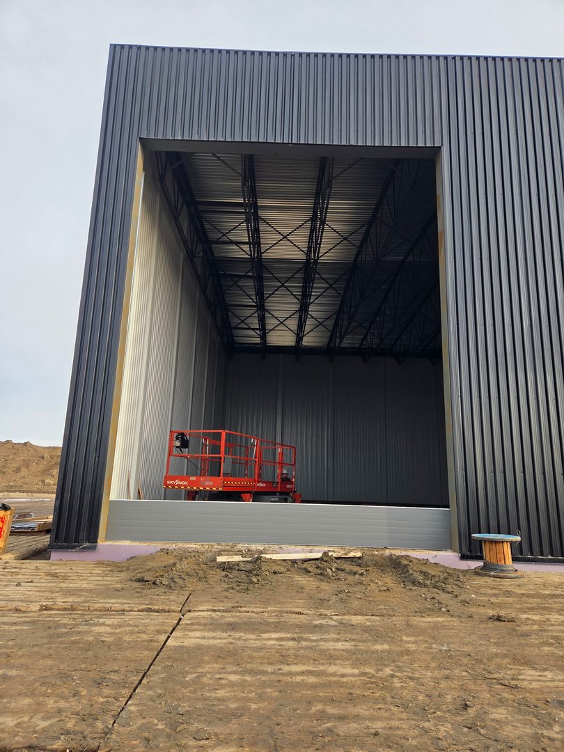 Tall commercial door opening under construction with a lift inside