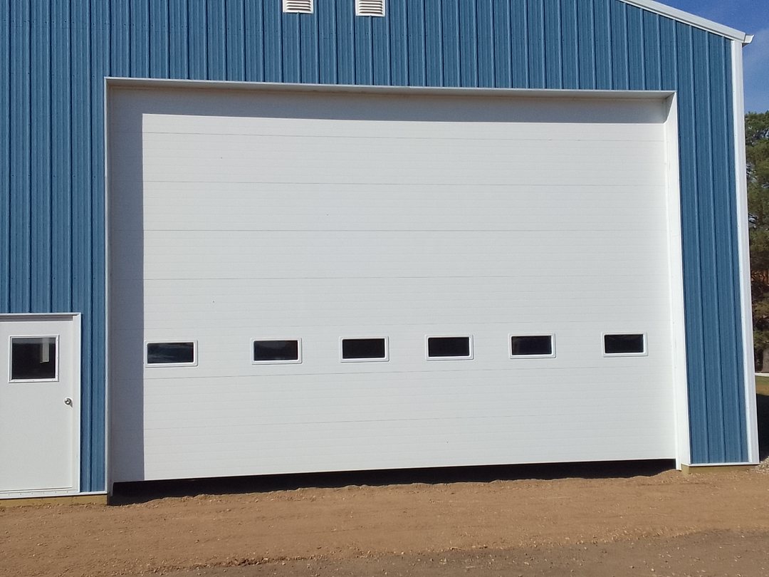 Large white commercial overhead door on a blue steel building