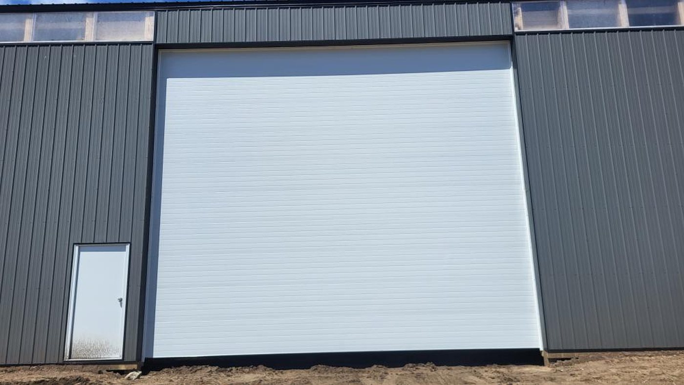 White sectional overhead door on a grey steel commercial building