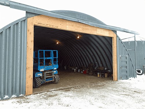 Overhead door opening framed into a quonset with a lift working inside