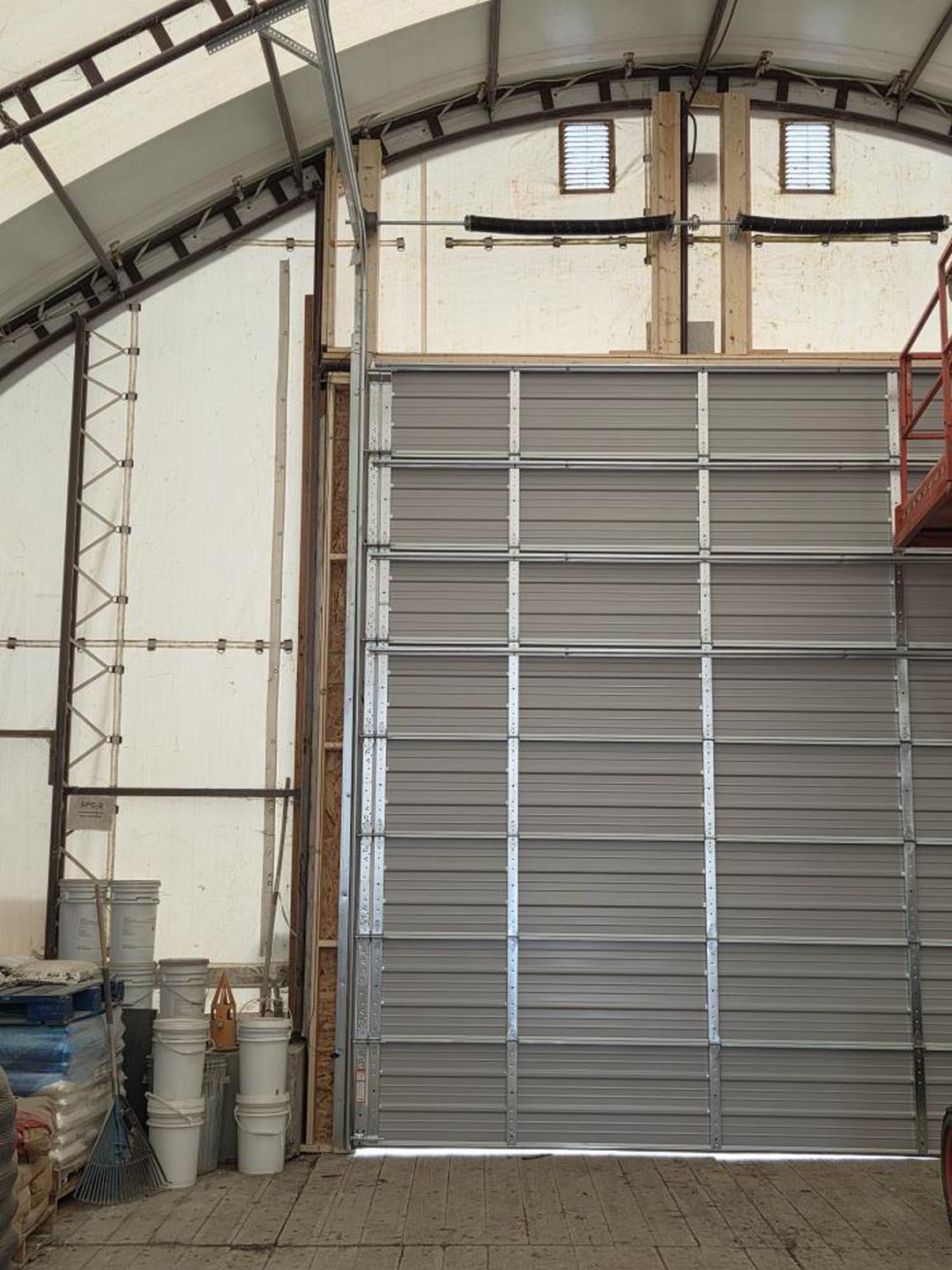 Tall overhead door frame fitted inside an arched quonset building