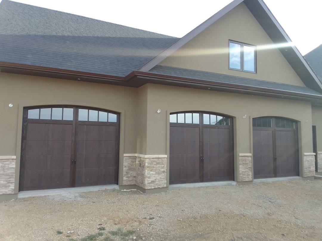 Three arched carriage-style garage doors on a stucco and stone home