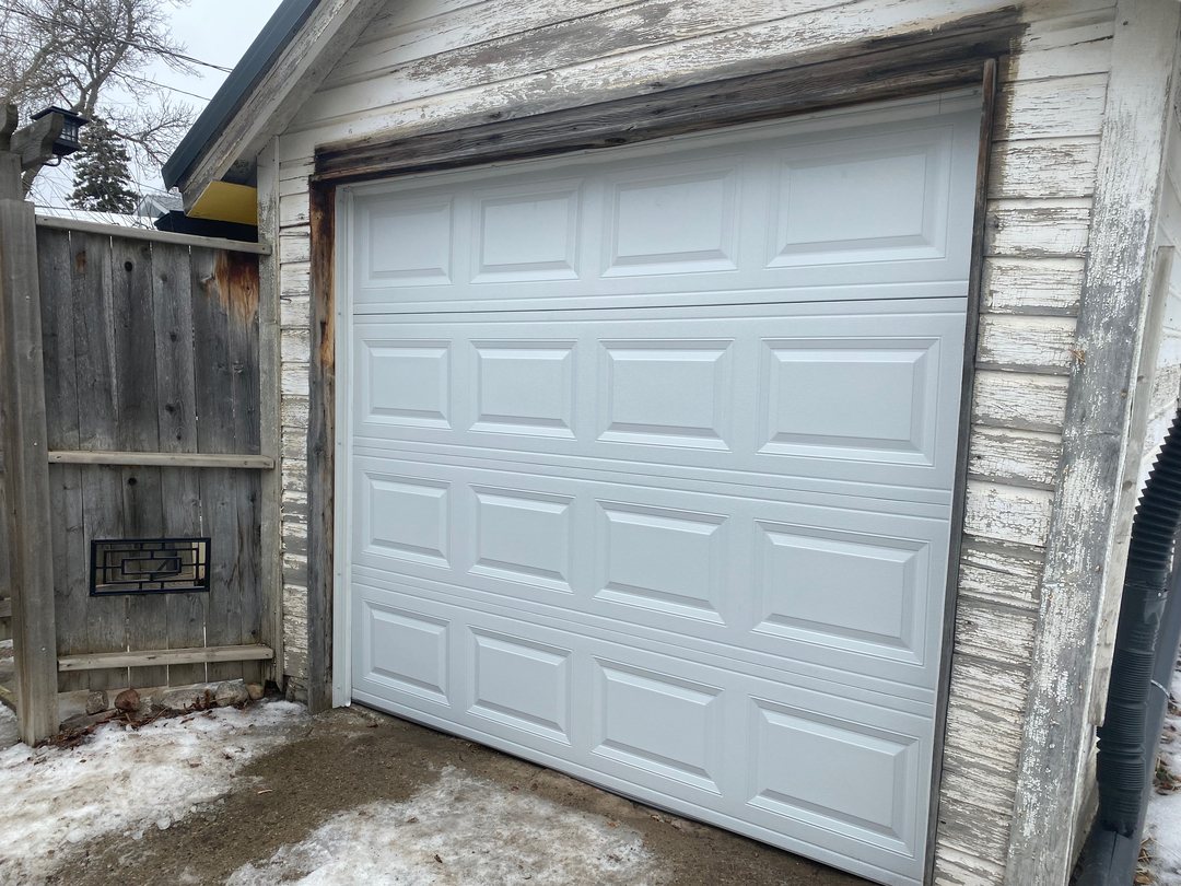 New white garage door fitted to an older detached garage