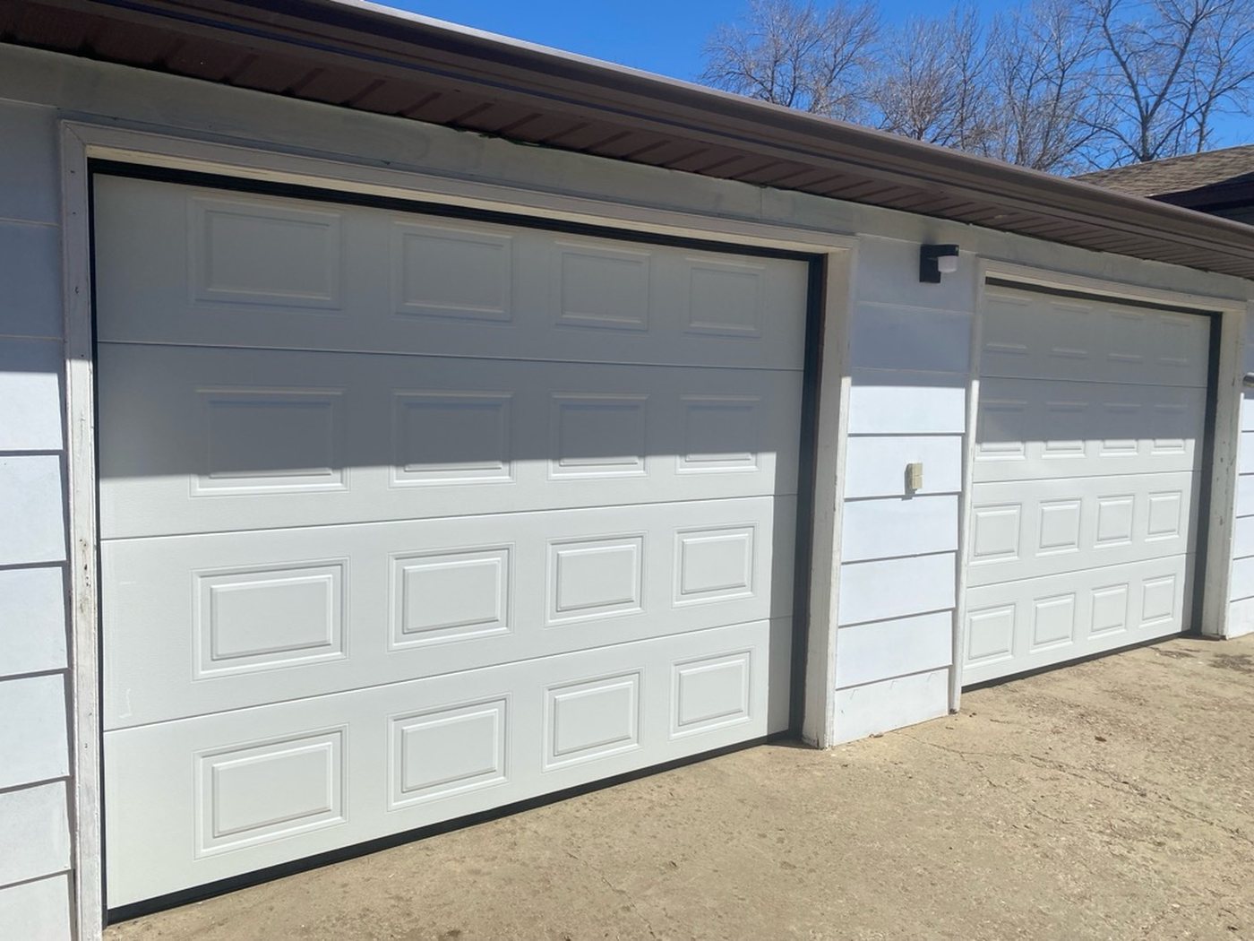 Two white raised-panel garage doors on a detached garage