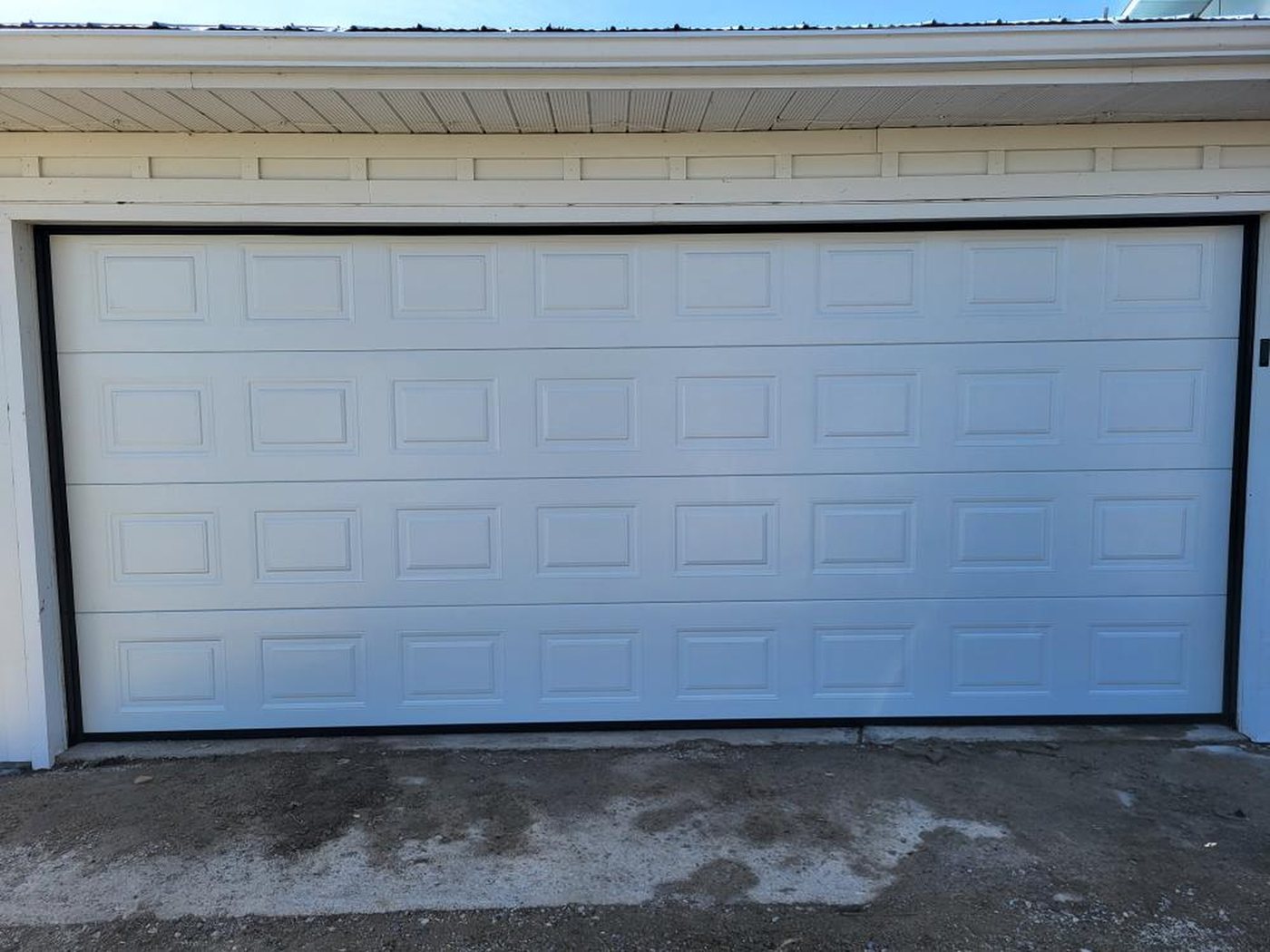 Wide white raised-panel garage door on a home